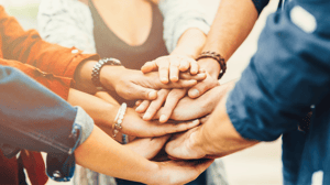 Hands of employees stacked to show them working together